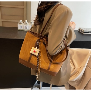 Close-up of vintage brown suede tote bag with cute biscuit plush charm and long tassels