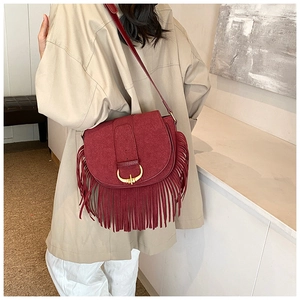 Detail shot of the burgundy PU suede crossbody bag with long fringes and gold buckle
