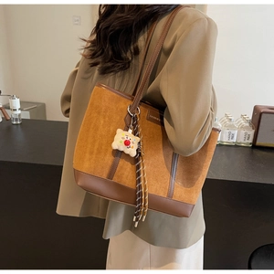 Detail of caramel brown tote bag with suede texture and cute teddy bear charm accessory