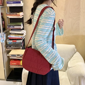 Detailed shot of a red quilted crossbody bag in soft padded fabric for autumn style