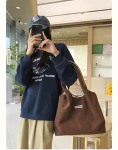 Gros plan d'un sac cabas en velours côtelé marron avec motif cœur rouge et étiquette