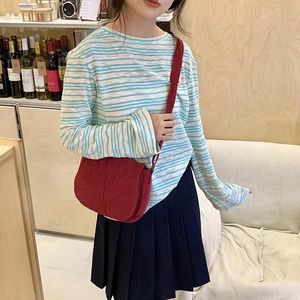 Red quilted crossbody bag with flap design worn by a model in a casual indoor setting