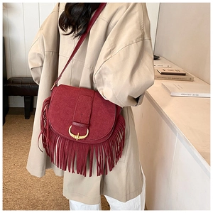 Detail of burgundy matte PU leather saddle bag with long tassels and gold U-shaped buckle