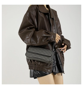 Detailed view of houndstooth crossbody bag with chain strap on a stylish model
