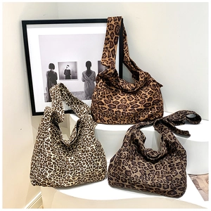 Three trendy leopard print cotton shoulder bags displayed on elegant white podiums