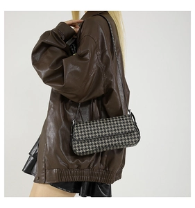 Close-up of houndstooth underarm baguette bag with slim leather strap on model