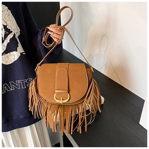 Detail of brown faux suede saddle bag with long fringe tassels and a gold horseshoe buckle