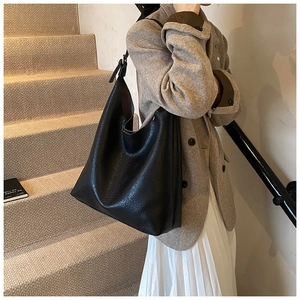 Close-up of black PU leather tote bag with lychee texture on a model in a stairwell