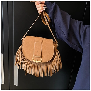 Close-up of bohemian brown matte suede saddle bag with long tassels and gold buckle
