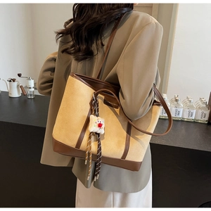 Detail of khaki PU leather tote bag with brown trim and plush charm in a cafe setting