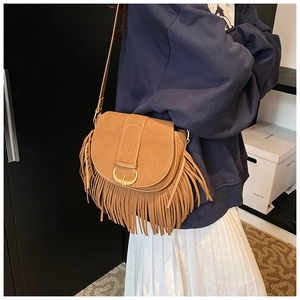Close-up of brown suede saddle bag featuring long fringes and horseshoe metal buckle