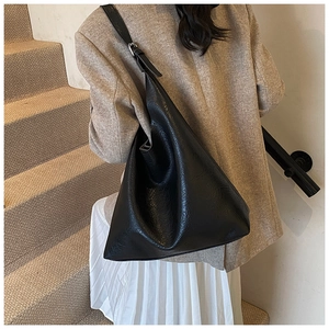 Detail view of slouchy black faux leather hobo bag with adjustable strap on shoulder