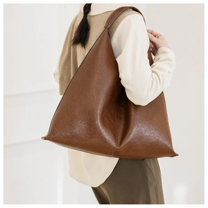 Detailed side view of a minimalist large brown PU leather tote bag worn over the shoulder