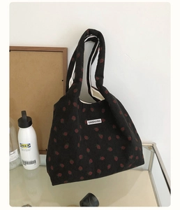 Détail d'un sac cabas en velours côtelé noir vintage avec motif fraises et étiquette
