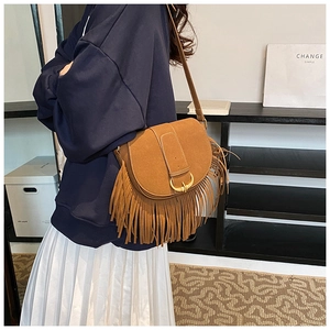 Detail of brown suede saddle bag featuring long fringe tassels and metallic buckle