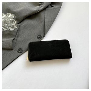 Chic black faux suede long wallet with gold zipper, styled with a modern office aesthetic