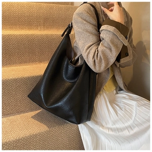 Detailed view of the black textured PU leather tote bag worn with an autumn outfit