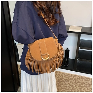 Close-up of brown suede crossbody bag with long fringe and golden horseshoe buckle