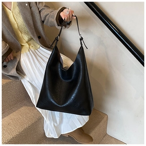 Detail of minimalist black PU leather tote bag with adjustable shoulder strap on stairs