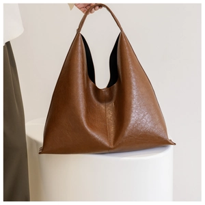 Detail of a minimalist dark brown PU leather tote bag with a smooth polished texture