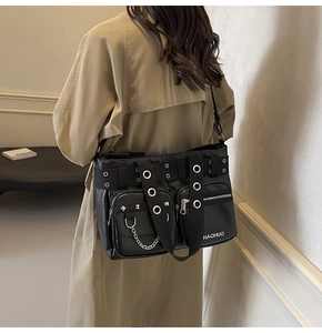 Detail of a black PU leather punk tote bag with silver metal eyelets and decorative chains