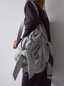 Detail of grey puffy cloud bag showing knot design and drawstring closure on shoulder
