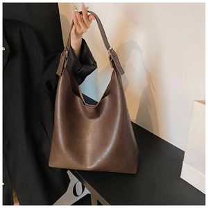 Detail of vintage brown PU leather tote bag with adjustable strap and metallic buckle
