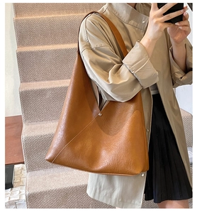 Detail shot of brown PU leather tote bag with natural texture and metal snap button