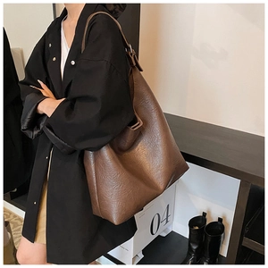 Detail of a large brown PU leather hobo bag with natural crinkle texture and wide strap