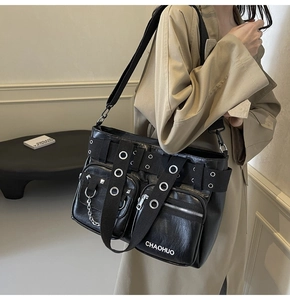 Detail of black PU leather shoulder bag with metal rings, studs and adjustable strap