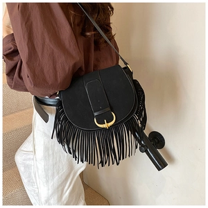 Close-up of bohemian black matte saddle bag featuring retro horn buckle and long fringe