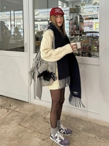 Outdoor street view of cream knit sweater and large grey puffer tote bag with bow detail