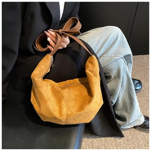 Détail du sac hobo en daim marron avec bandoulière réglable dans un décor de studio
