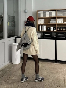 Rear view of a beige chunky cable knit oversized sweater in a casual street style