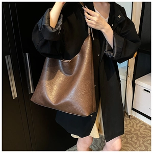 Detail of coffee brown PU leather tote bag with soft texture and natural folds for women