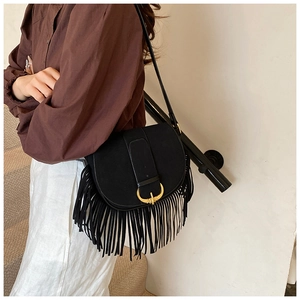 Detail of black matte saddle bag featuring long fringes and a gold horseshoe buckle