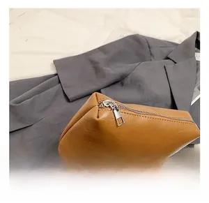 Detailed close-up of brown litchi pattern PU leather handbag with silver metal zipper