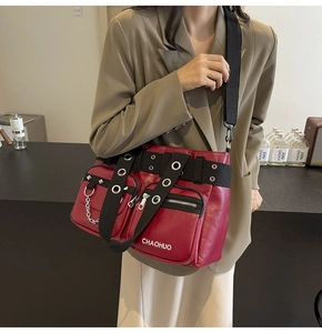 Close-up of dark red PU leather crossbody bag with multiple zippers and wide nylon strap