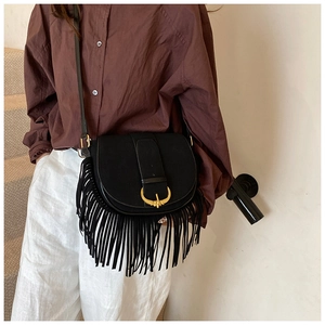 Detailed view of black PU suede crossbody bag with long fringe and gold curved buckle