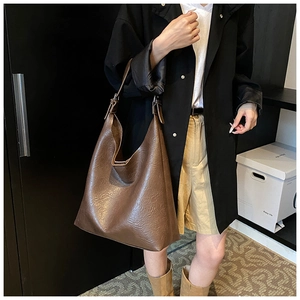 Detailed view of brown pleated PU leather tote bag worn by model in casual outfit