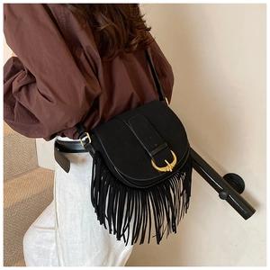 Close-up of black PU suede saddle bag with gold metal buckle and long leather tassels