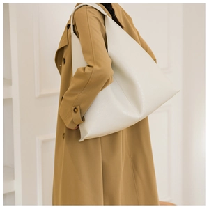 Minimalist white PU leather shoulder bag with triangle silhouette shown on model