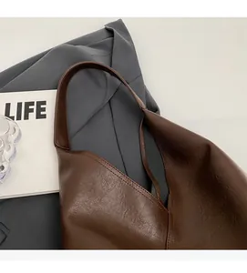 Close-up of brown soft leather tote showing premium lychee grain texture and wide strap