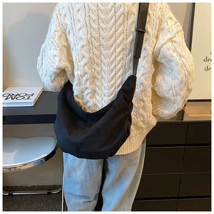 Détail du sac bandoulière croissant noir minimaliste avec bandoulière réglable sur pull