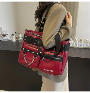 Detail of red punk faux leather tote bag with silver rivets, chains and heavy metal studs
