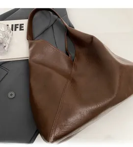 Close-up of brown faux leather tote bag with soft texture and wide shoulder strap
