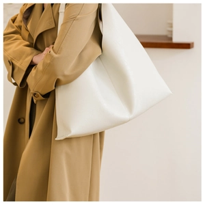 Detail view of large cream PU tote bag showing soft pebble texture and wide shoulder strap