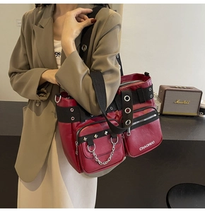 Detail of dark red PU leather shoulder bag with industrial silver eyelets and chains