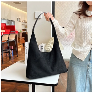 Detail of minimalist black matte PU leather shoulder tote bag in a lifestyle cafe setting