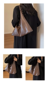 Macro view of dark brown oversized leather tote bag showing soft texture and glossy finish